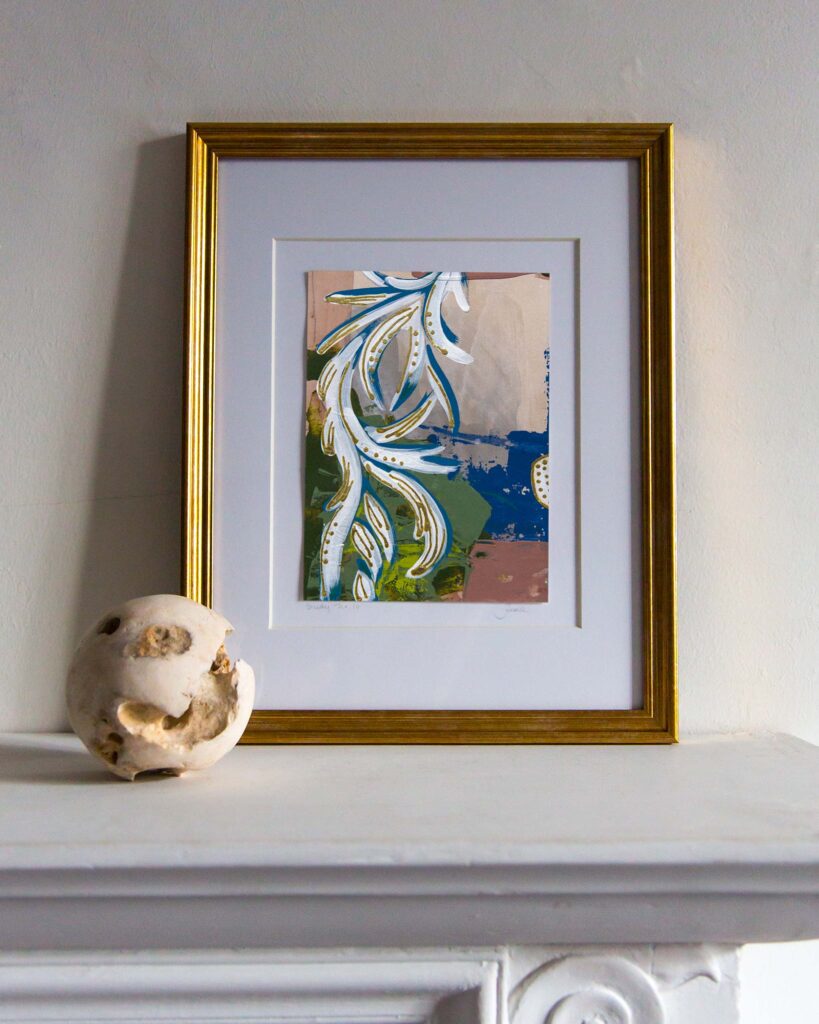 Straight on mantel view of an abstract architectural painting by Teale Hatheway featuring a scrolling neoclassical rinceau motif in white and blue with gold leaf embellishments. The stylized foliate tendrils sweep diagonally across a layered background of olive green, cobalt blue, and soft parchment, evoking classical ornament through contemporary brushwork and color.