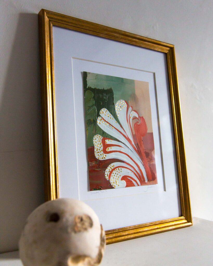 Angled view of Teale Hatheway’s Forma Coloris Lux Mentis — Study No. 3 framed in gold with a double mat, resting on a white mantel. The image highlights the swirling architectural motif and hand-applied gilding, with a sculptural stone sphere in the foreground.