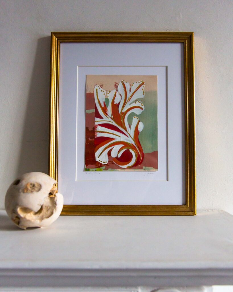 Framed architectural painting, Forma Coloris Lux Mentis — Study No. 6 by Teale Hatheway, displayed on a white mantel in a gold frame with a double mat. The artwork features a sweeping ornamental flourish with hand-applied gilding, complemented by a sculptural stone sphere.