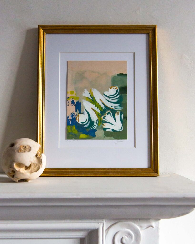 Framed architectural painting, Forma Coloris Lux Mentis — Study No. 8 by Teale Hatheway, displayed on a white mantel in a gold frame with a floating mat. The artwork features sweeping white ornamental forms with gilded accents layered over abstract blocks of green, blue, and soft peach tones, accompanied by a sculptural stone sphere.